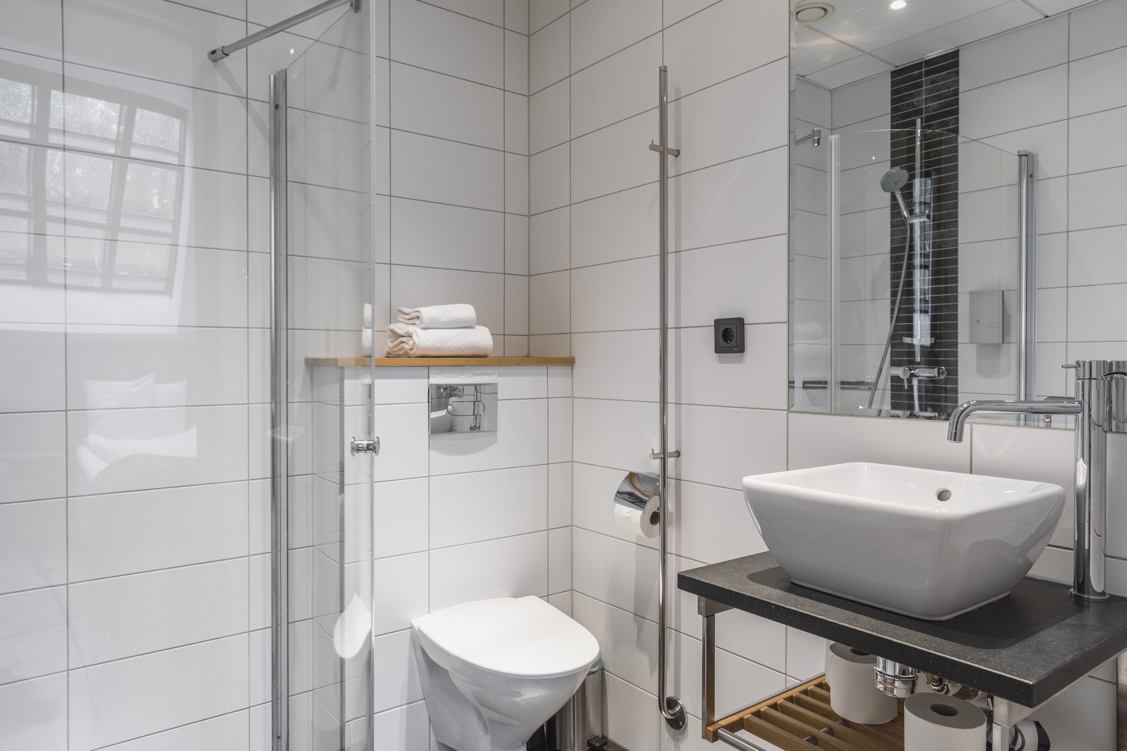 Une salle de bain moderne avec une douche à parois de verre, un lavabo blanc et des toilettes.