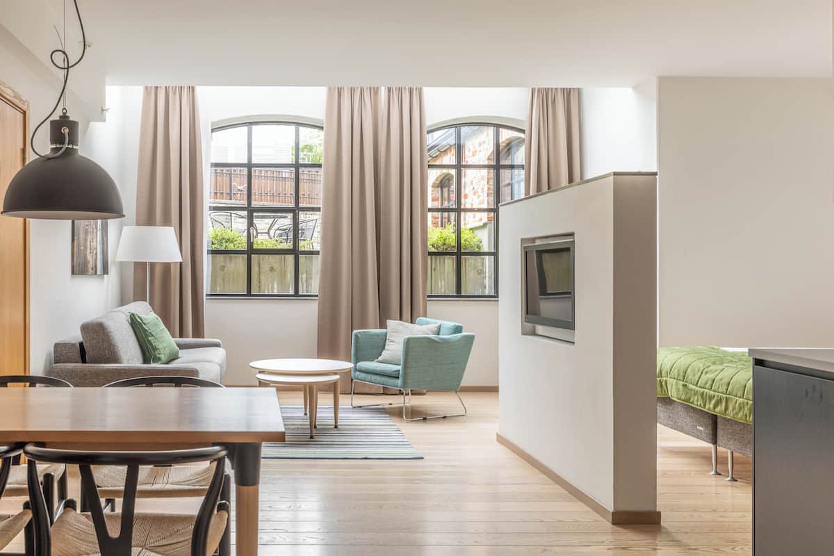 A modern living room with a dining area, a TV, and a bed.
