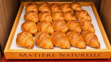 A wooden box labeled 'MATIÈRE NATURELLE' containing a dozen golden-brown croissants.