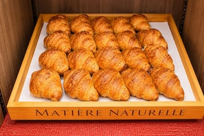 A wooden box labeled 'MATIÈRE NATURELLE' containing a dozen golden-brown croissants. - Almont Inn Nihonbashi (Tokyo)