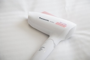 A Panasonic hair dryer with a white body and a pink handle, placed on a white surface. - Almont Inn Nihonbashi (Tokyo)