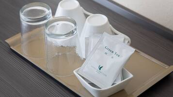 A tray with a glass, two cups, and a bowl containing tea packets.