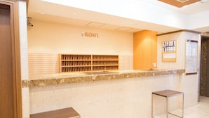 A reception desk with a 'FRONT' sign, a wooden shelf, and two bar stools. - Almont Inn Nihonbashi (Tokyo)