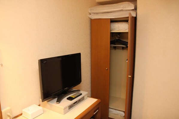 Une télévision posée sur un meuble, une télécommande et un appareil blanc, vraisemblablement un lecteur DVD, dans une chambre d’hôtel.