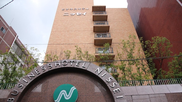 Il cartello dell'Hotel Business Niseki con logo, circondato da una struttura in pietra curva.