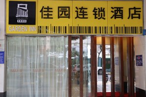 A hotel entrance with a yellow sign reading "Garden Inn" and Chinese characters.