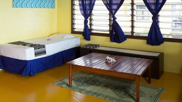 Una habitación con una cama, una mesa de madera y un ventilador de techo.