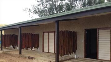 A building with a covered outdoor area, multiple doors, and a dirt ground.