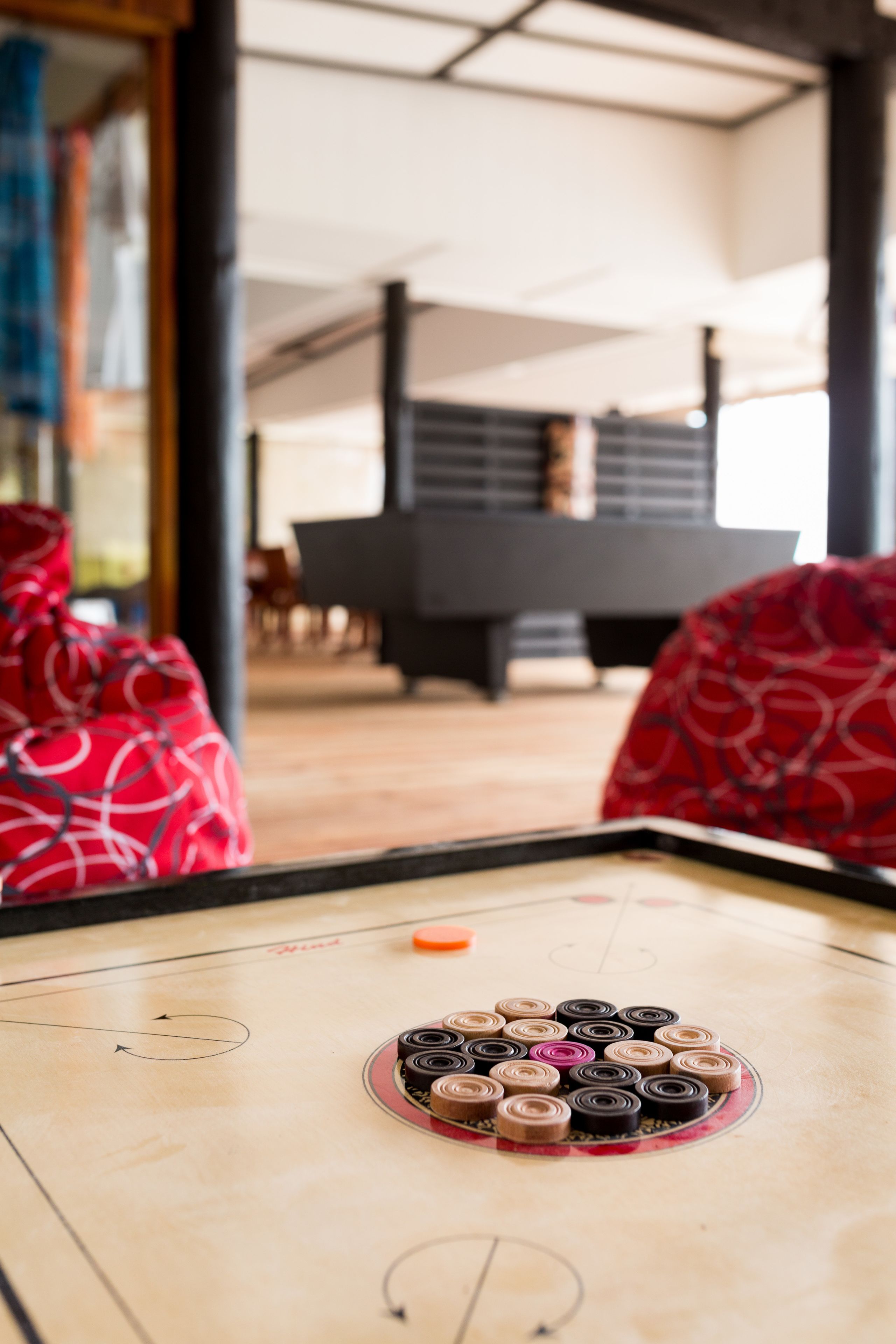 A table with a game in progress, a piano in the background, and red patterned seating.