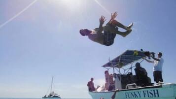 Iemand springt van een boot genaamd 'Funky Fish' in het water.