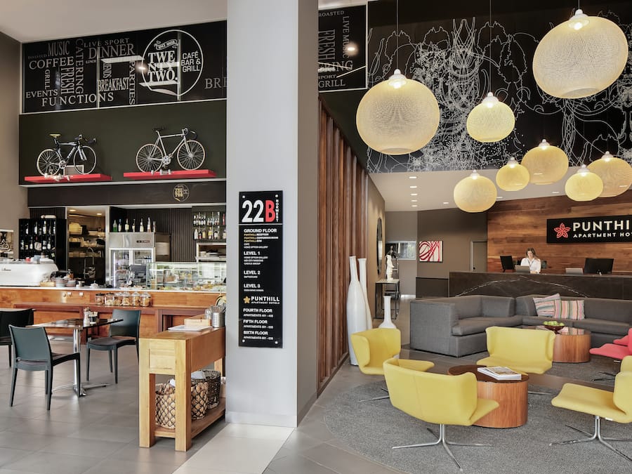 Eine moderne Hotelhalle mit Rezeption, Sitzgelegenheiten und einer Kaffeebar.