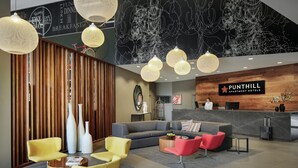 A modern hotel lobby with a reception desk, sofas, and a wooden partition. - Punthill Norwest (Norwest)
