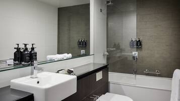 Un baño moderno con cabina de ducha de vidrio, un lavabo blanco y un espejo grande.