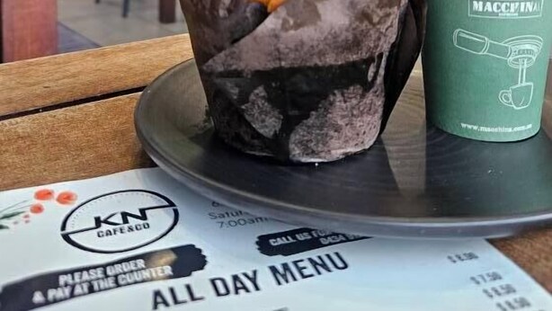 A muffin in a paper cup on a table with a menu in the foreground. - Punthill Norwest (Norwest)