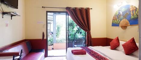 A hotel room with a bed, a sofa, a TV, and a view of the outdoors.