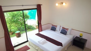 Une chambre avec un grand lit, une table de chevet, une fenêtre avec des rideaux et une vue sur la verdure.
