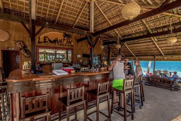 A bar area with wooden furniture and a thatched roof. - Levantin (Boracay Island)