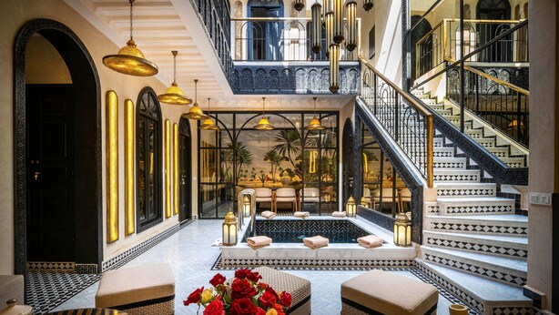 A luxurious lobby with a central seating area, a pool, and a grand staircase. - Riad L'Etoile D'Orient (Marrakech)