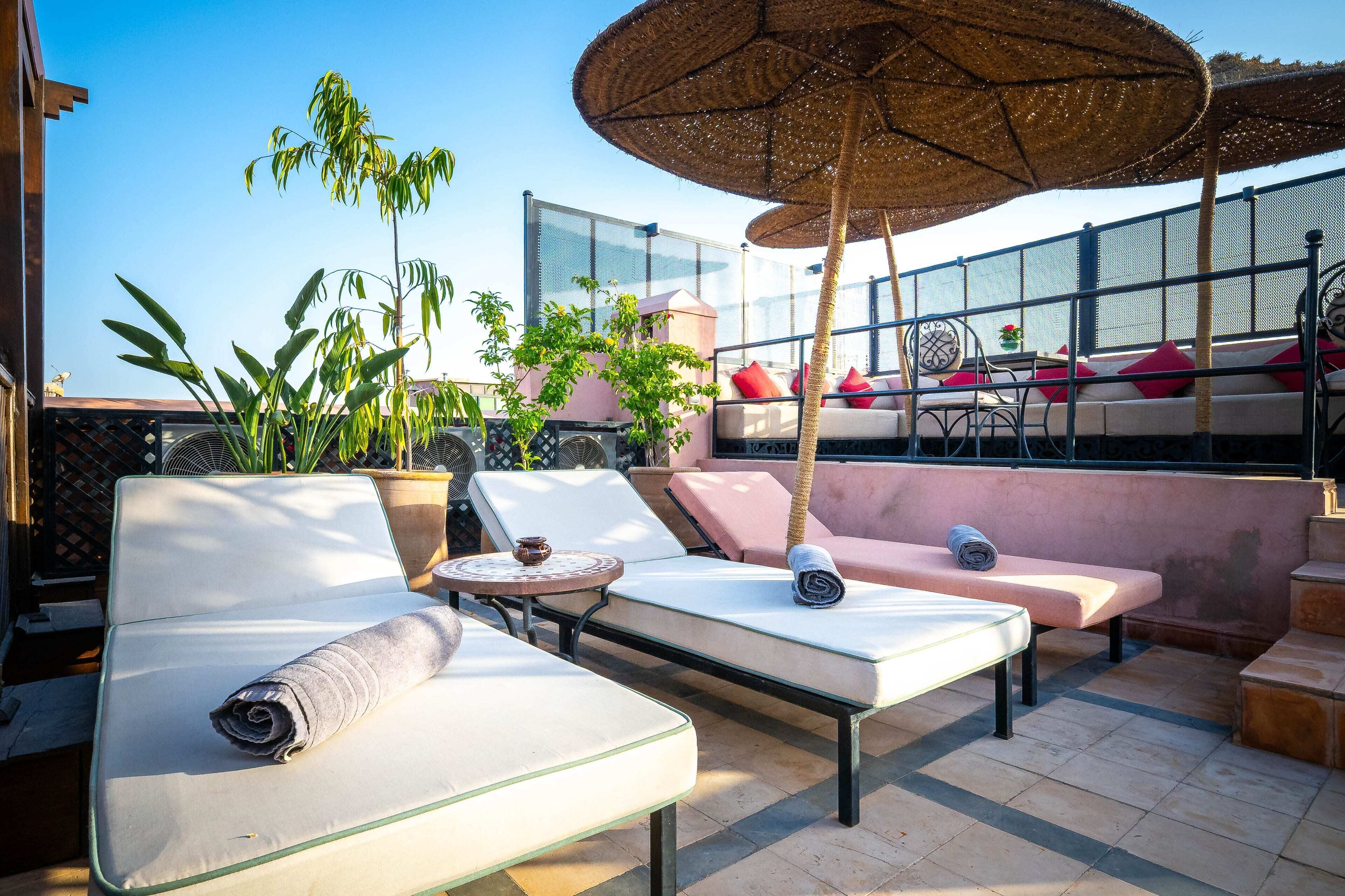 Een dakterras met loungezetels, een tafel en een grote parasol.