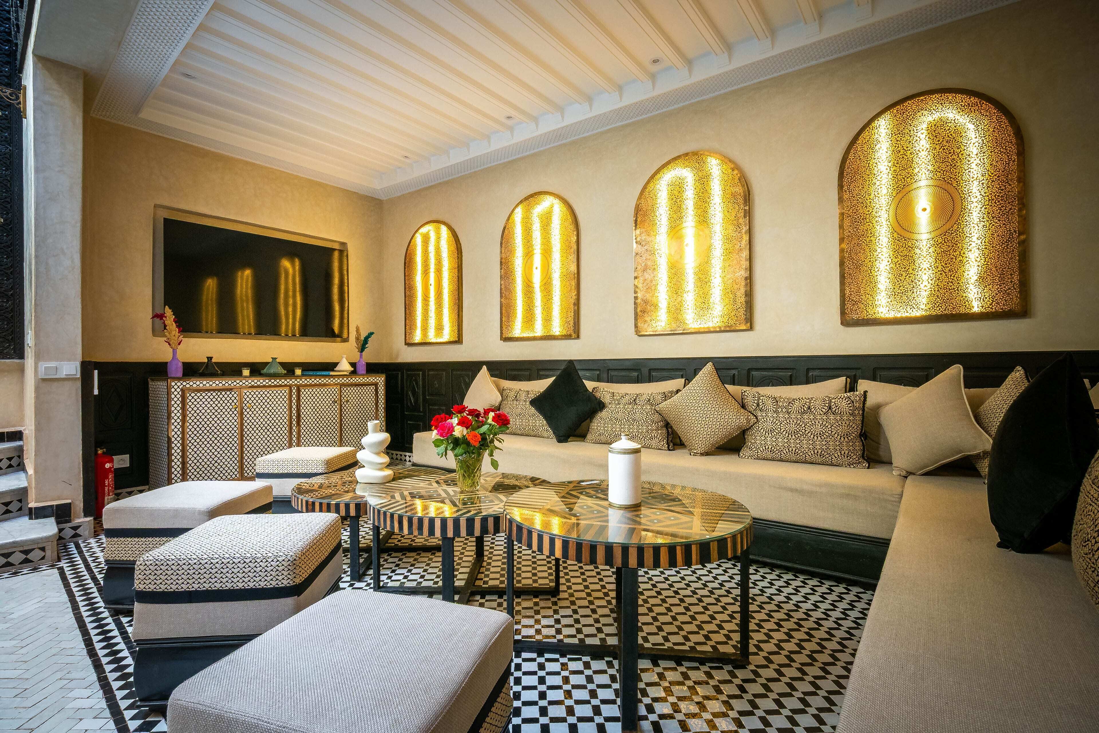 A modern interior with a sofa, ottomans, a round table, and patterned flooring.