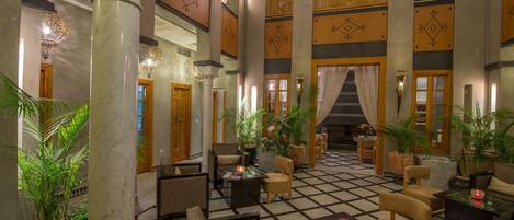 A lobby with a checkered floor, multiple seating areas, and large columns.