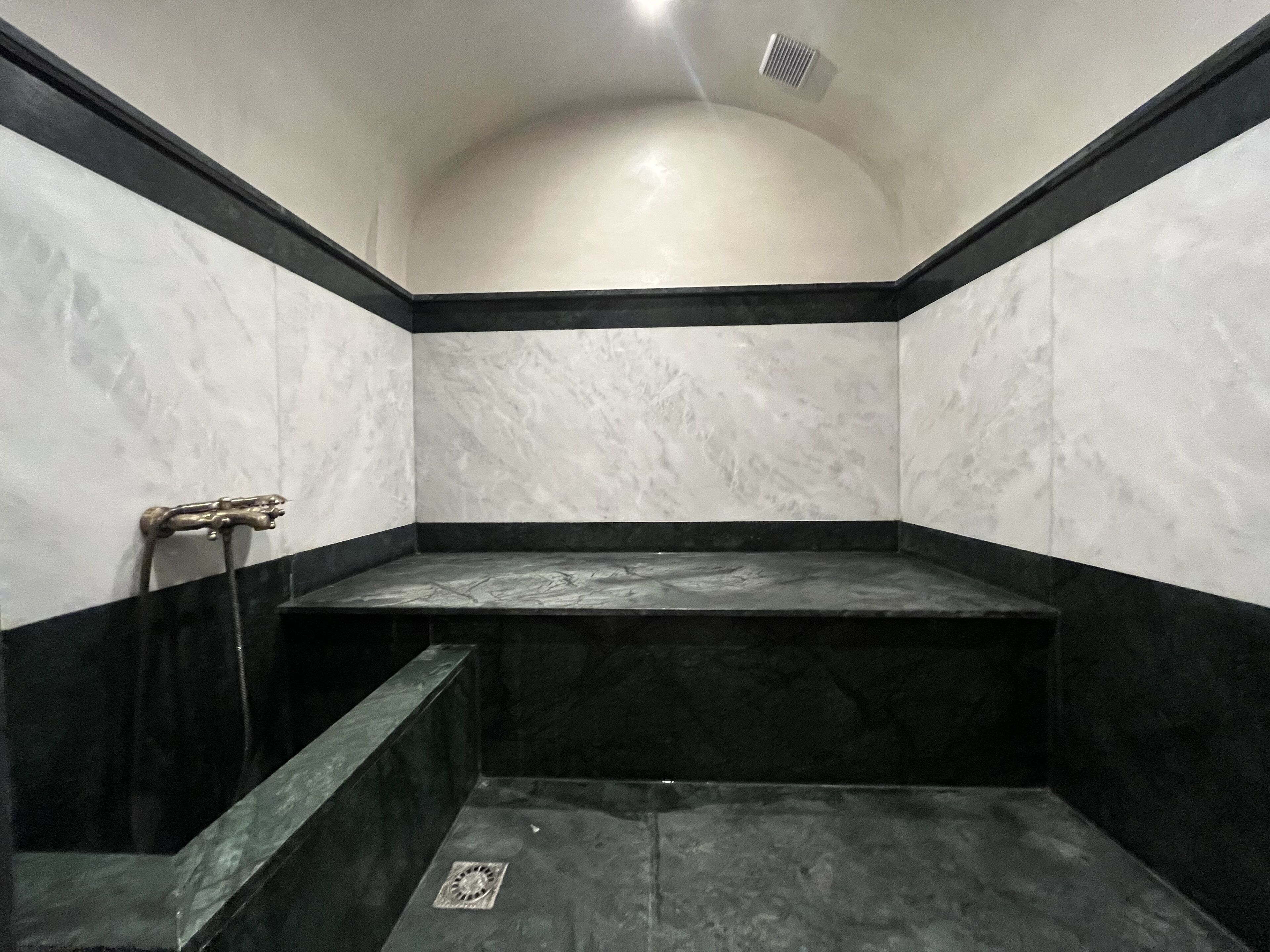 A bathroom with a black and white marble design, a shower area, and a visible drain.