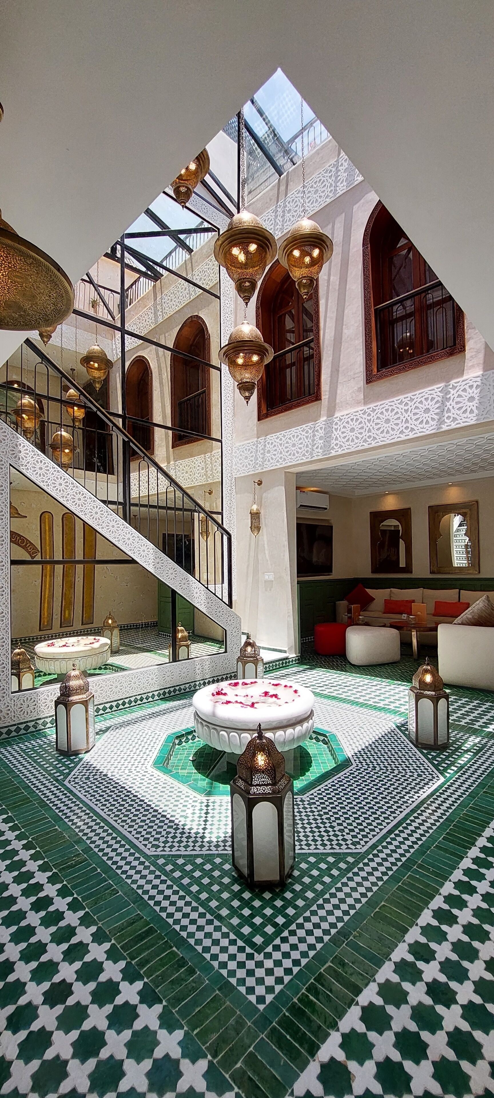 A spacious interior with a central fountain, ornate lighting, and a high ceiling with skylights.