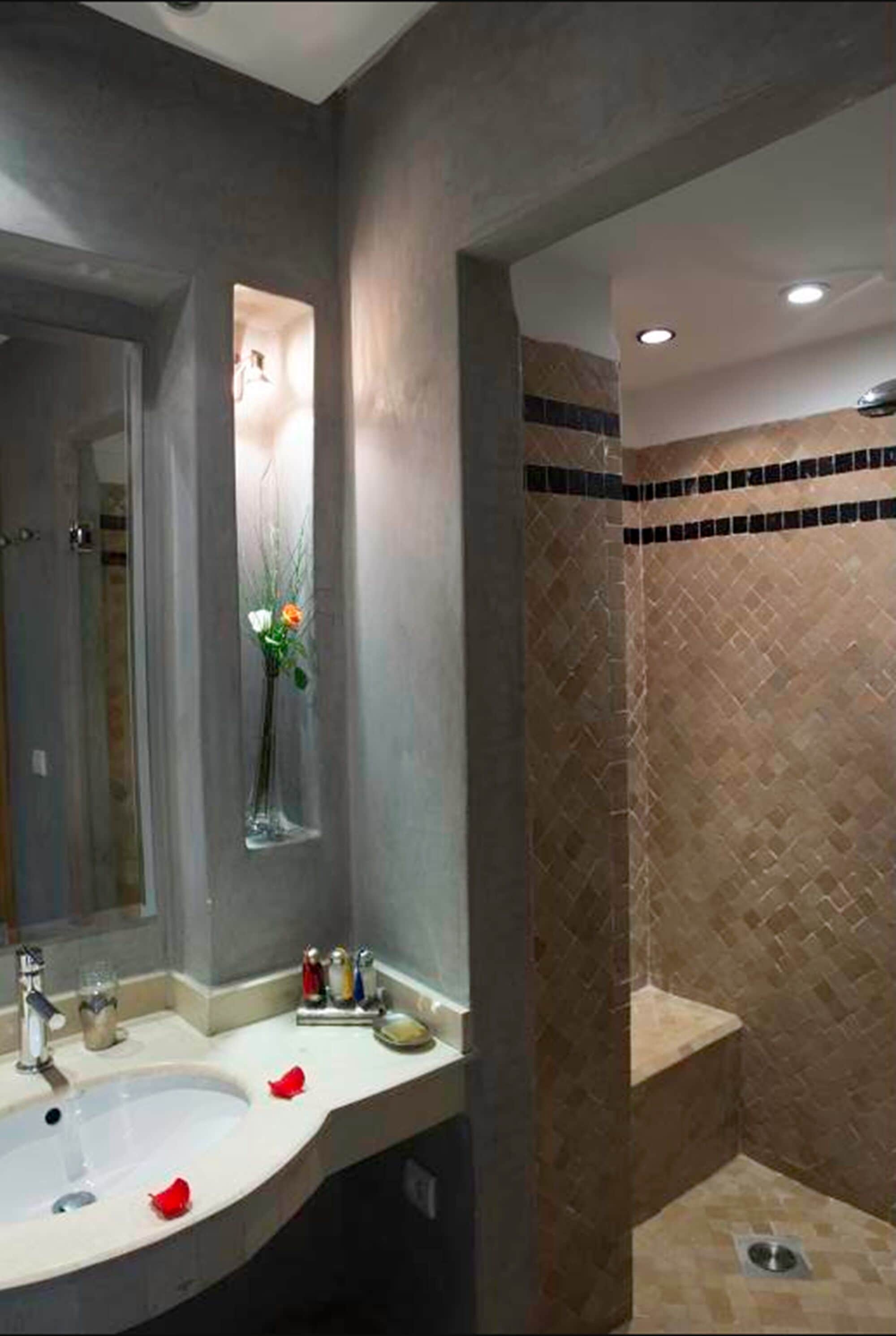 A modern bathroom with a large mirror, a sink, and a shower area.