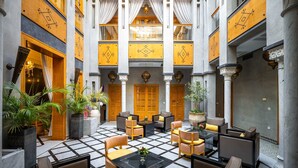 A hotel lobby with a checkered floor, multiple seating areas, and a central staircase. - Riad L'Etoile D'Orient (Marrakech)