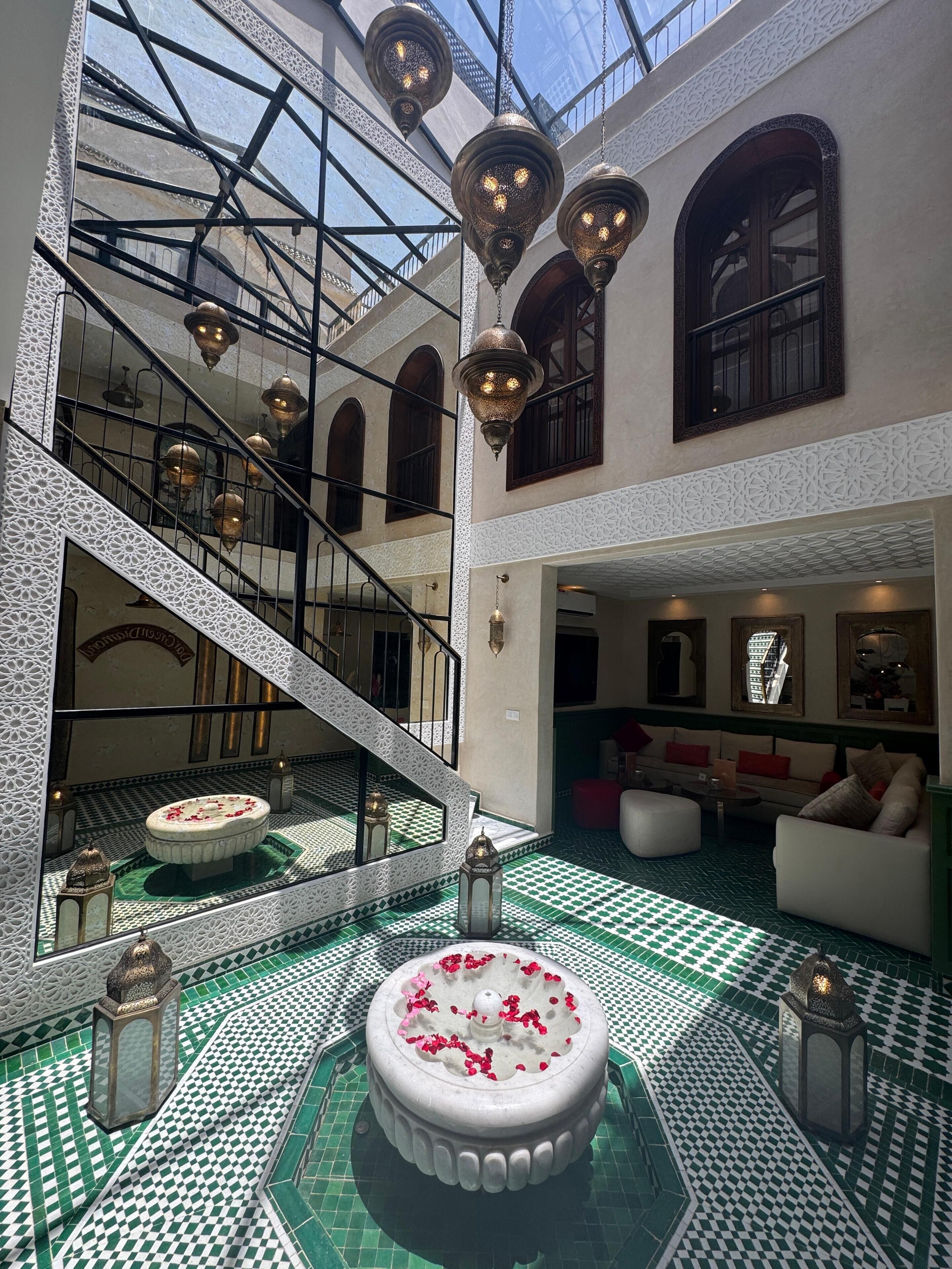 A spacious interior with a central fountain, ornate lighting, and a staircase leading to upper levels.