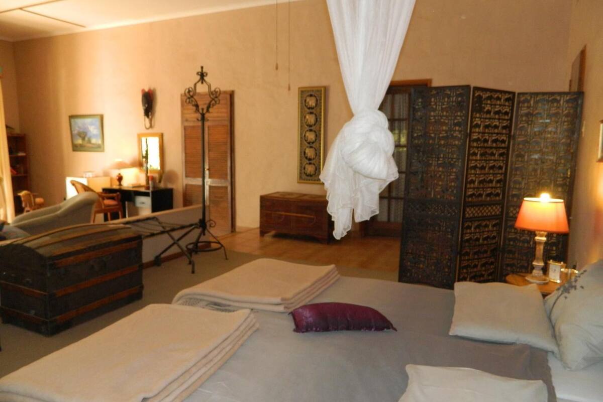 A hotel room with a bed, a desk, a chair, a wardrobe, and a large decorative screen.