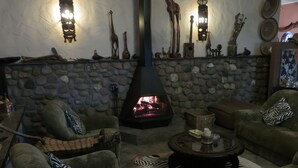 A cozy living room with a stone fireplace, green sofas, and various decorative items on the mantel.