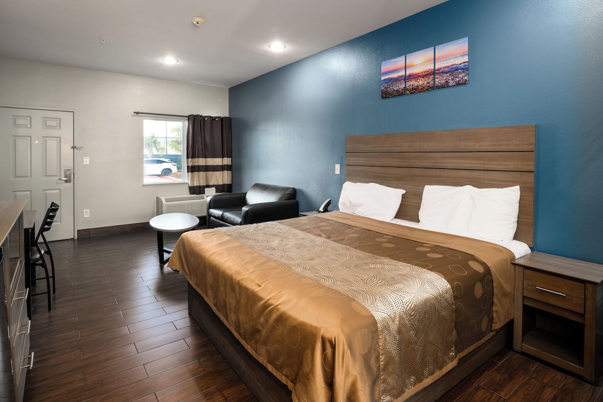 Quarto de hotel com uma cama grande, uma escrivaninha e uma cadeira.