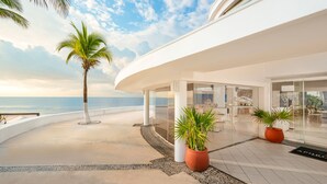 A modern hotel with a curved exterior, palm trees, and a view of the ocean. - Desire Pearl Riviera Maya Resort – All Inclusive, Exclusively for Couples (Puerto Morelos)