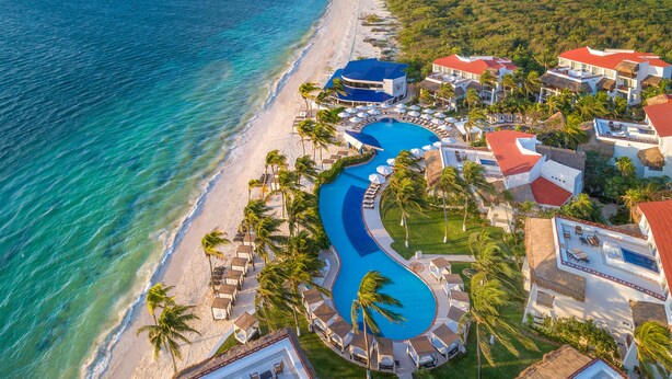 An aerial view of a resort with a curving pool, beachfront, and multiple buildings with red roofs. - Desire Pearl Riviera Maya Resort – All Inclusive, Exclusively for Couples (Puerto Morelos)