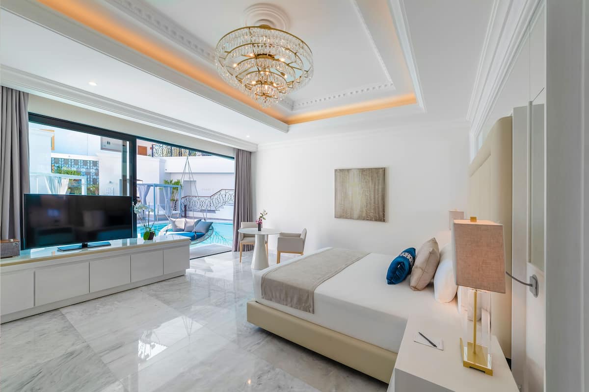 Una habitación de hotel moderna con una cama grande, televisión, escritorio y balcón con vista a la piscina.