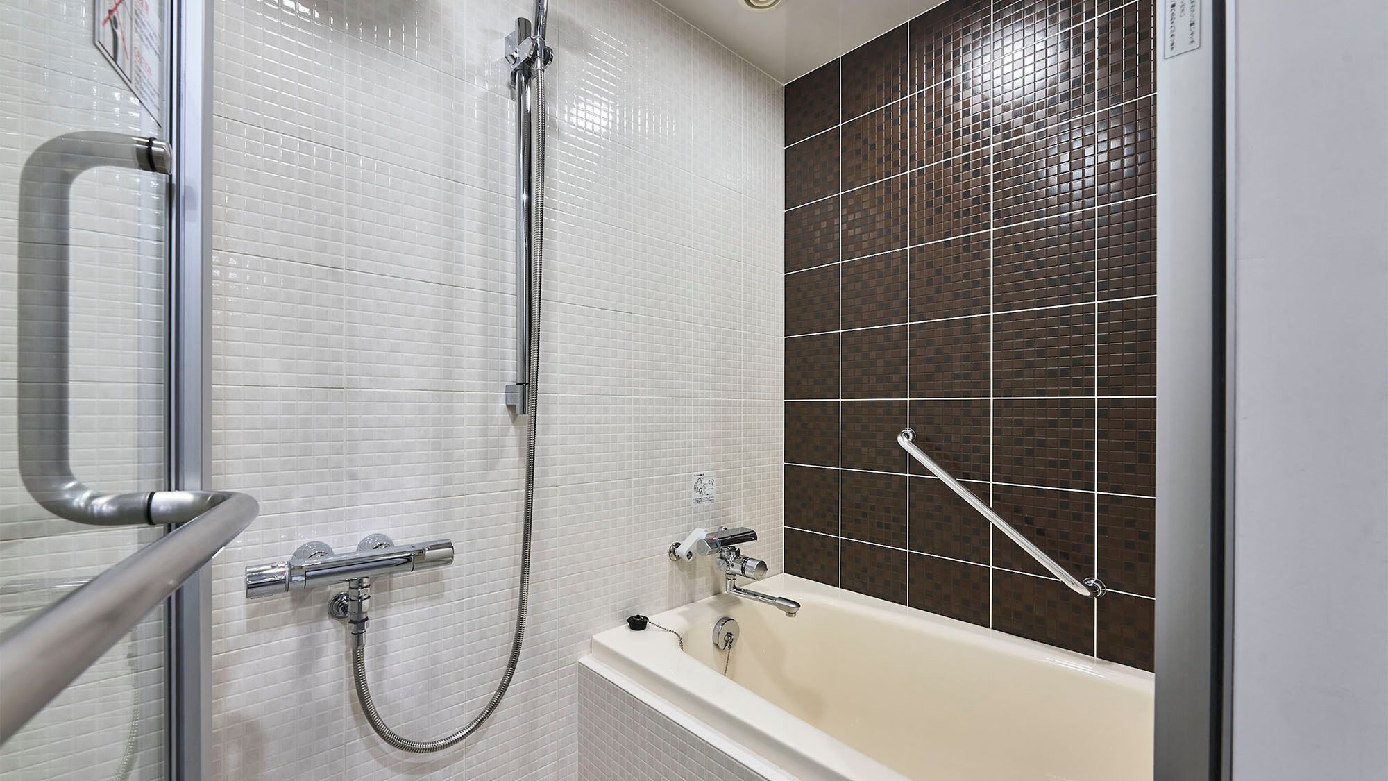 A bathroom with a glass shower enclosure, a bathtub, and a tiled wall.