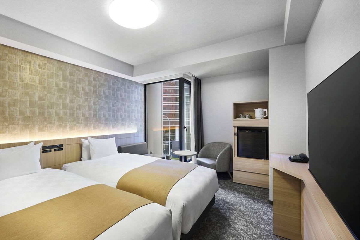 Une chambre d’hôtel avec deux lits, un bureau, une chaise, une télévision et une fenêtre donnant sur un beau paysage.