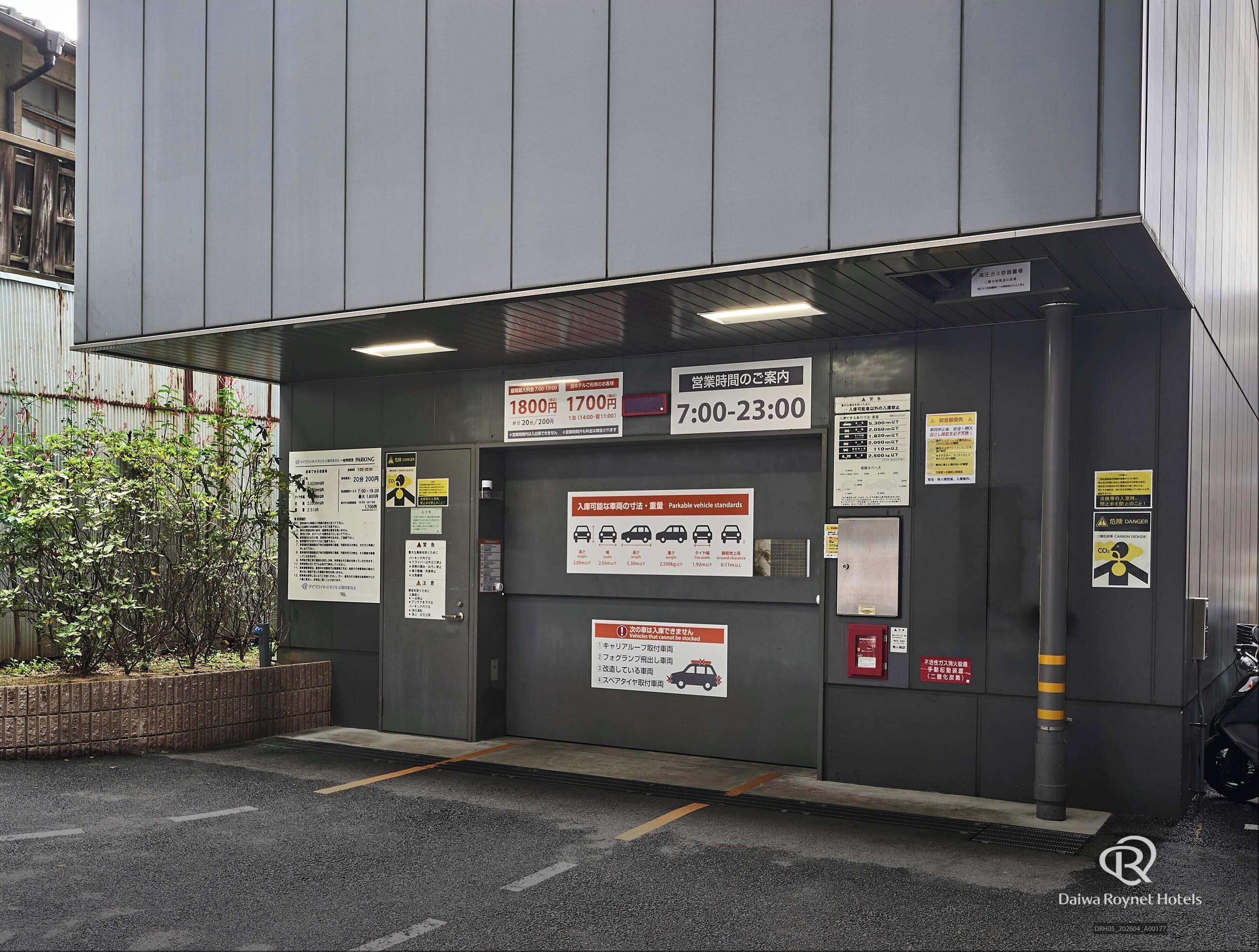 A hotel entrance with parking signs, operating hours, and various notices.