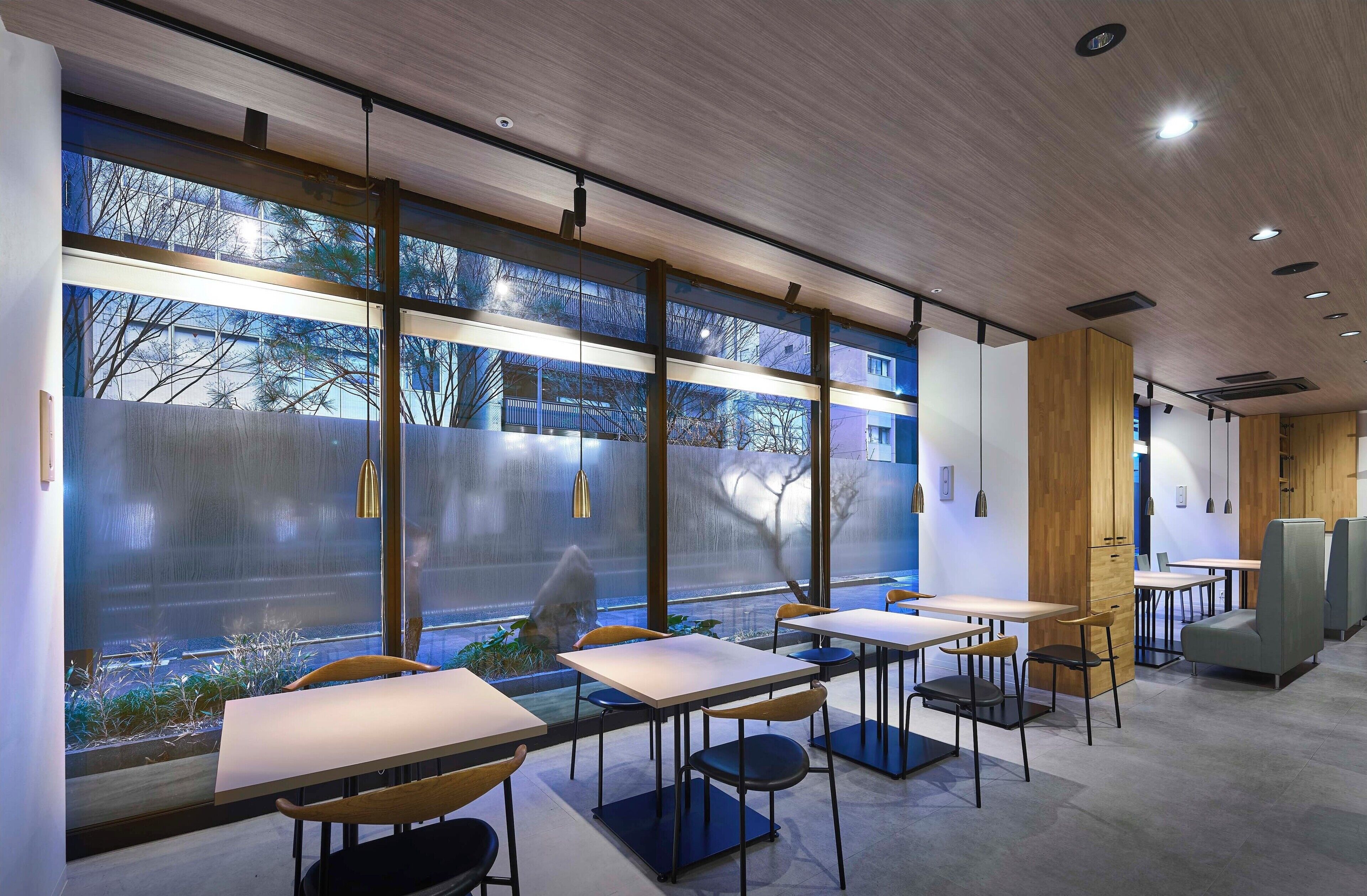A modern interior with tables and chairs, large windows, and a wooden ceiling.