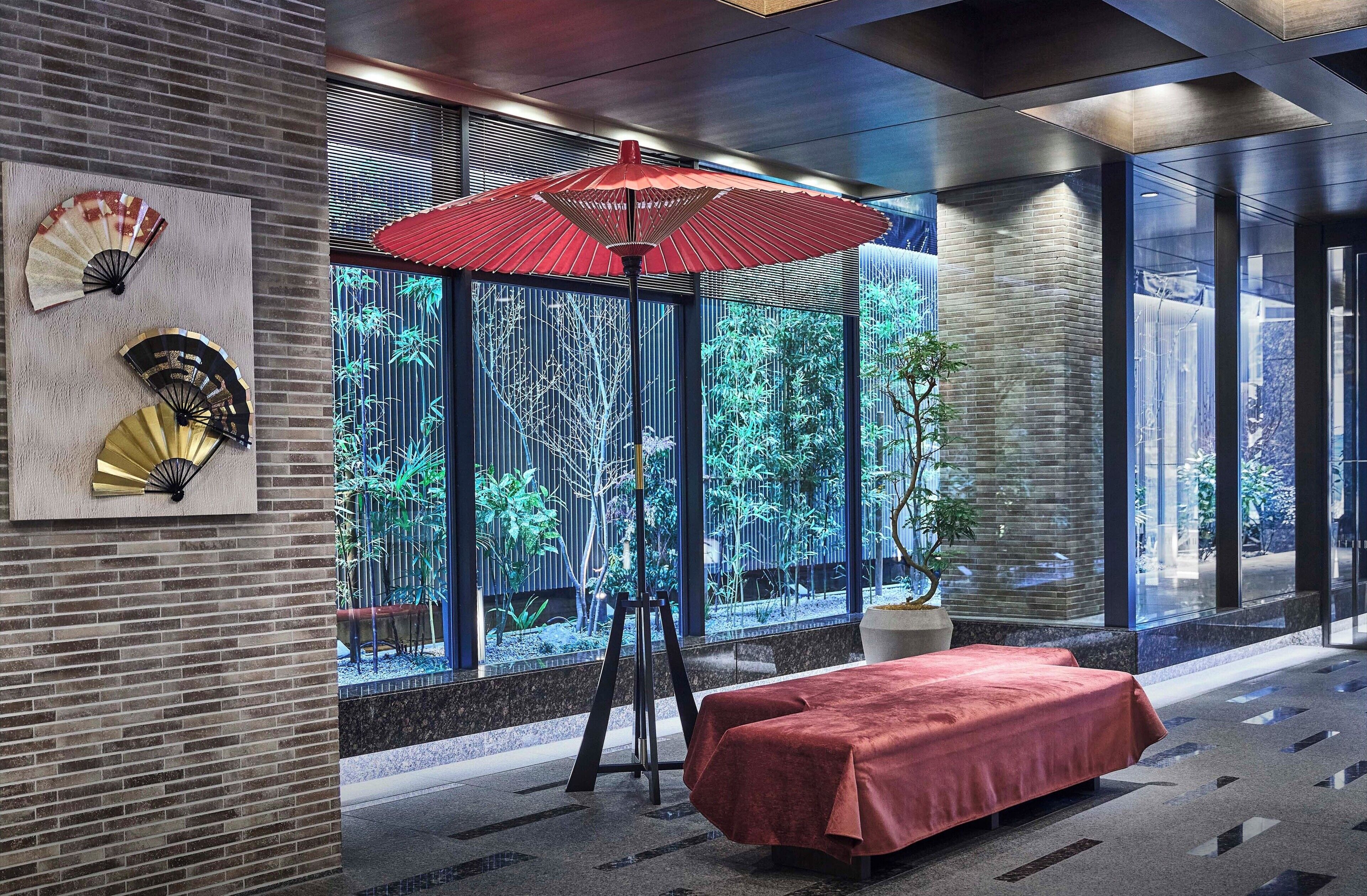 A modern interior with a large window, a red umbrella, and a brick wall.