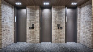 A modern elevator area with four elevators, each with a digital display and a control panel.