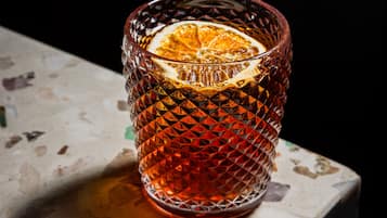 Un vaso transparente con un diseño texturizado y una rodaja de naranja en su interior.