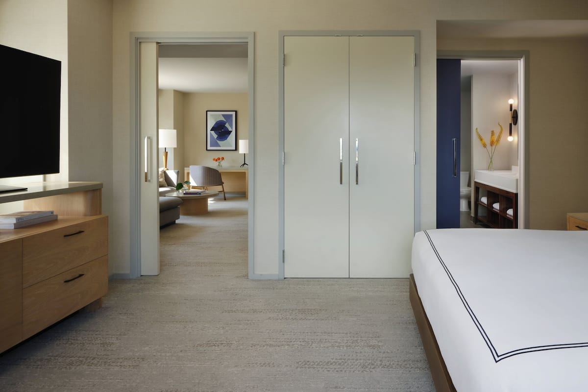 A hotel room with a bed, a TV, a desk, and a bathroom.