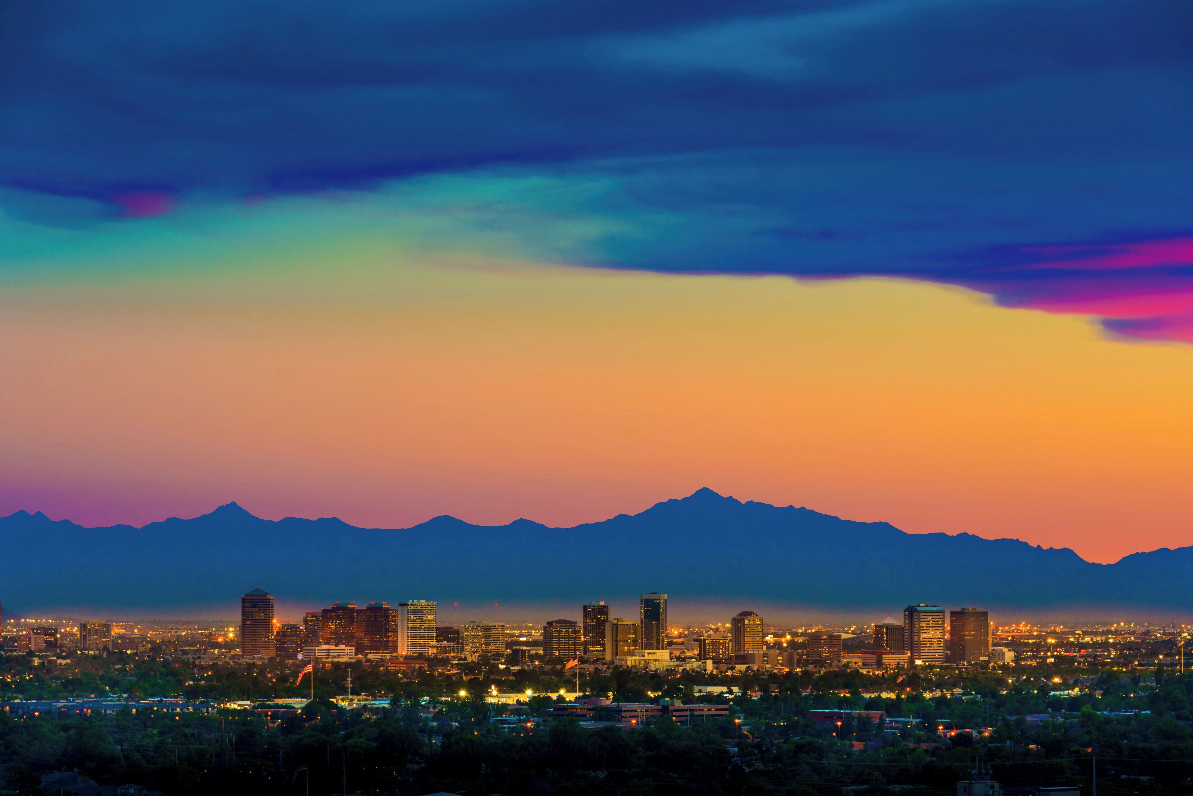 A cityscape with a mountain range in the background and a skyline of buildings.