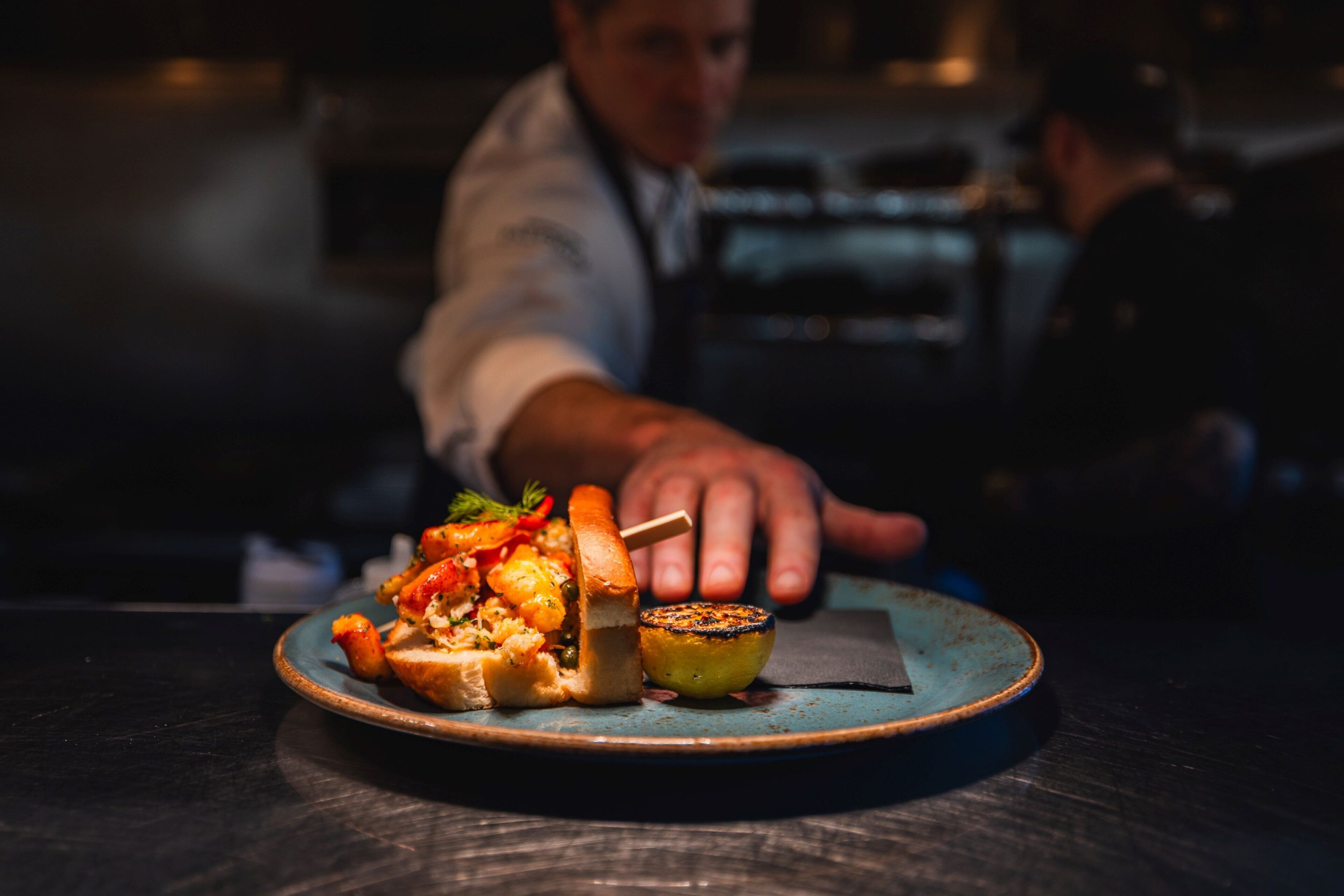 A plate of food with a partially eaten sandwich and a grilled vegetable on a blue plate.
