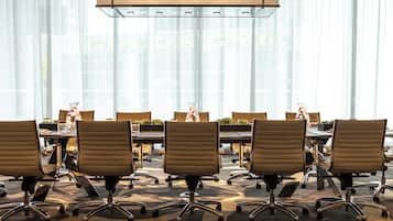 A conference room with a long table, multiple chairs, and a modern ceiling light fixture.
