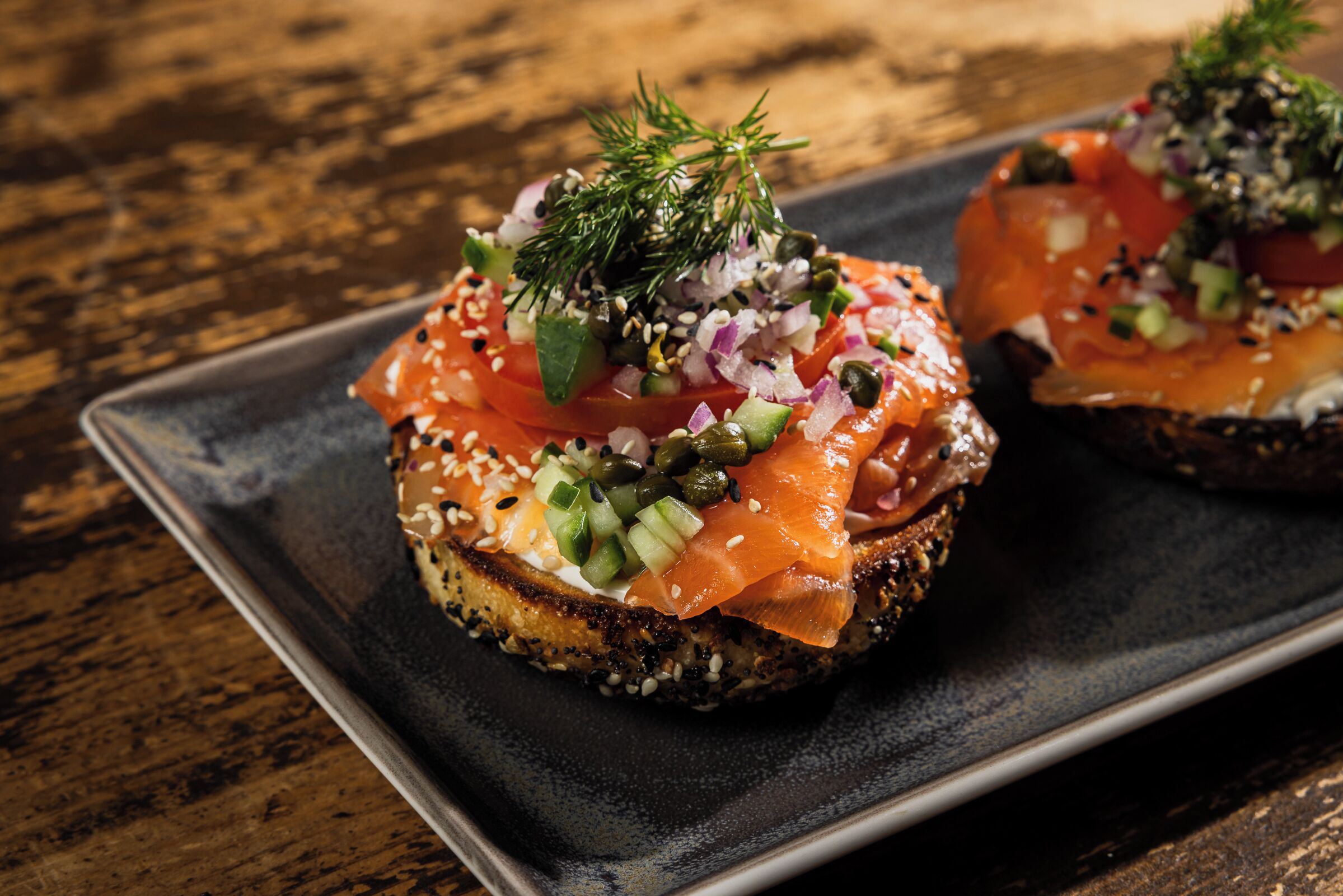 Two open-faced sandwiches on a dark plate.
