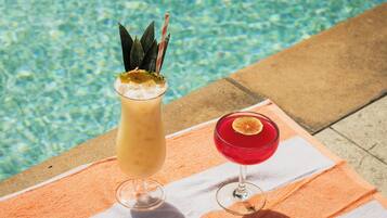 Two drinks on a striped towel by a pool.