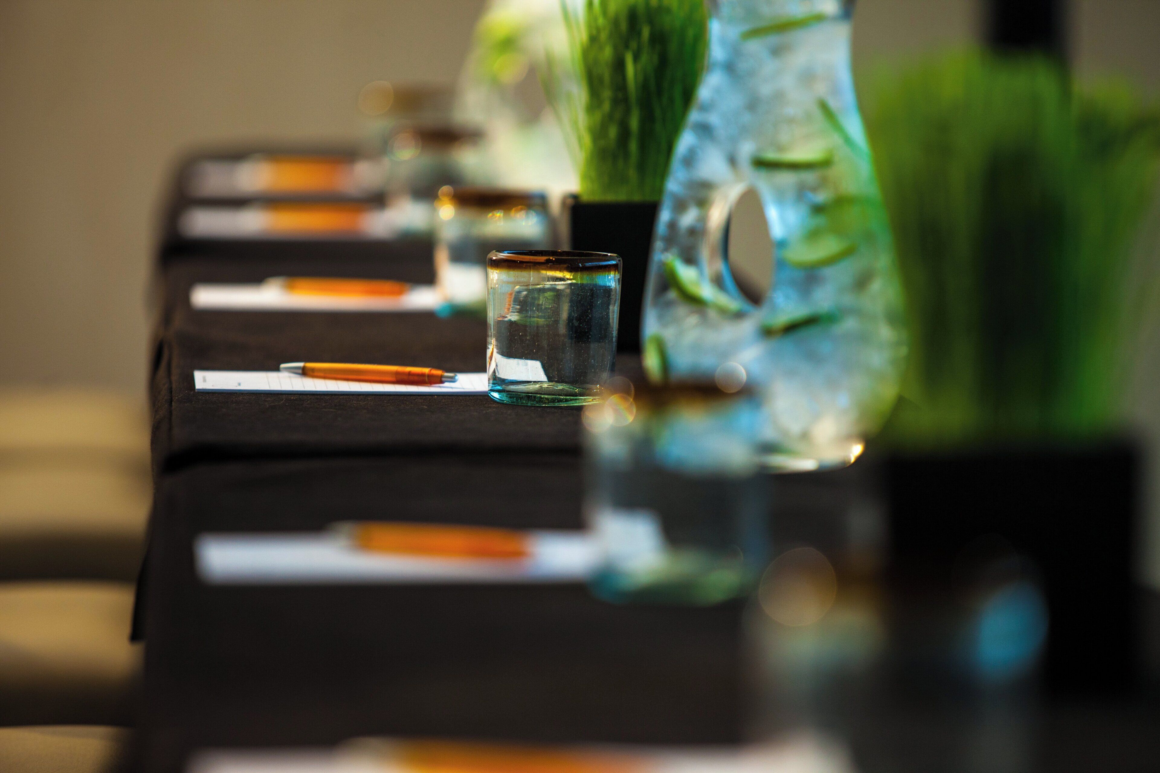 A table with a glass of water, a pen, and a notepad.